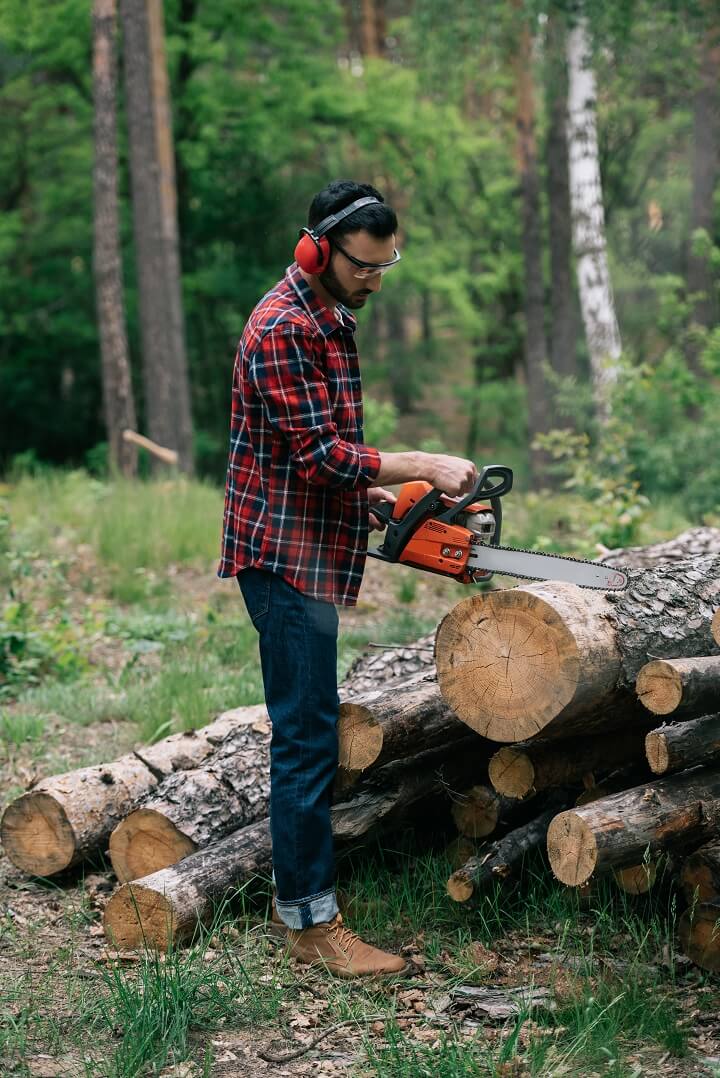 Man Cutting Wood With Chainsaw
