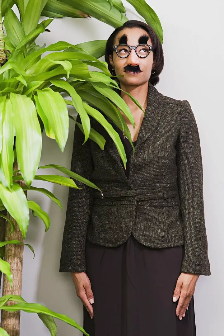 Woman In Disguise Behind Plant